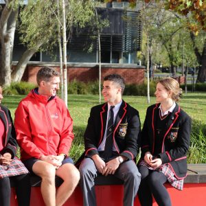 Ballarat Clarendon College high school students sitting down smiling and talking to each other.
